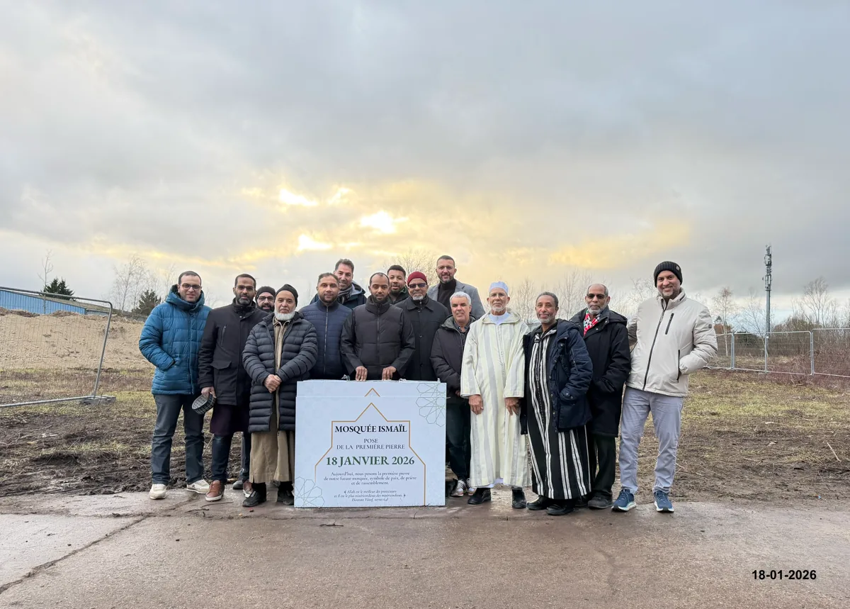 Les membres du bureau posent sur le terrain autour de la première pierre, une plaque blanche marquée « Mosquée Ismaïl, pose de la première pierre, 18 janvier 2026 »