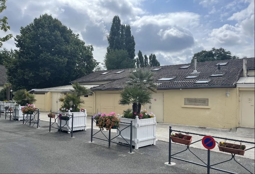 Le bâtiment de la Mosquée Ismaïl, bas et aux murs clairs, devant une allée fleurie
