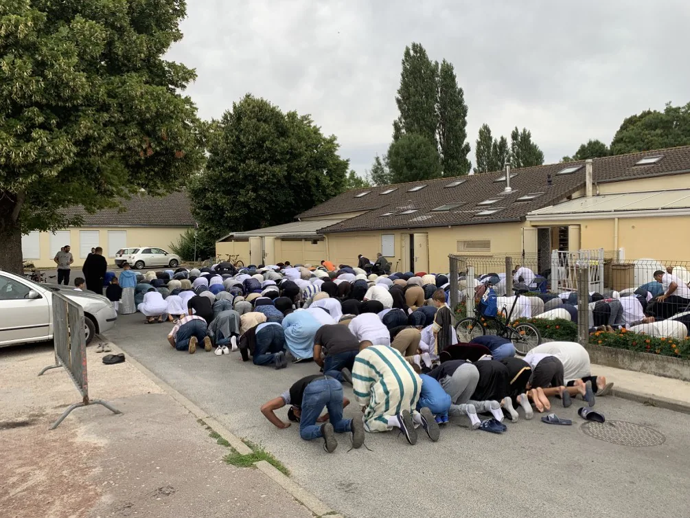 Fidèles prosternés en rangs dans la rue, devant la mosquée