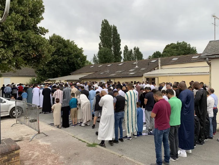 Fidèles debout en rangs devant le bâtiment de la mosquée